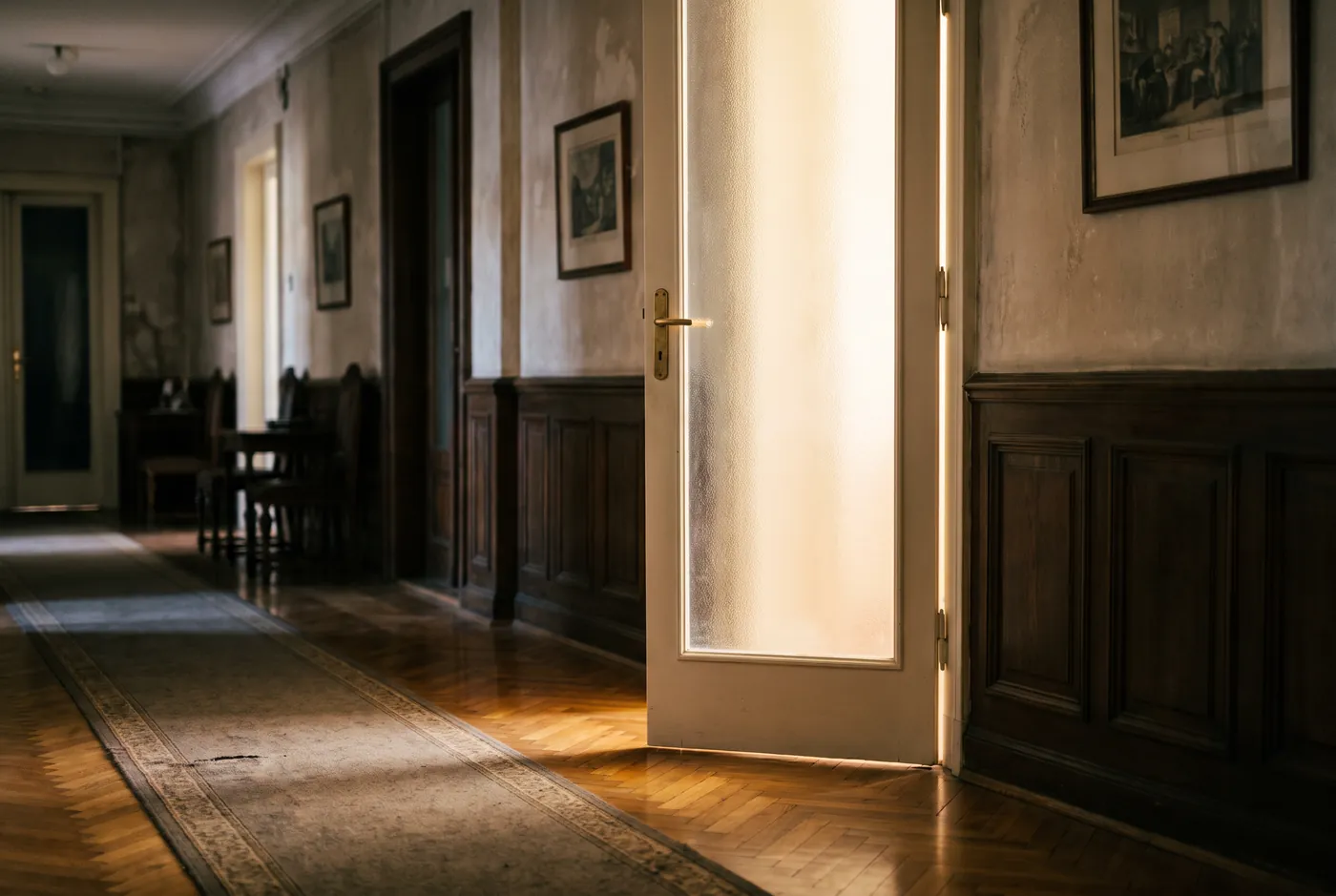 Frosted-glass office door slightly ajar in a wood-panelled corridor