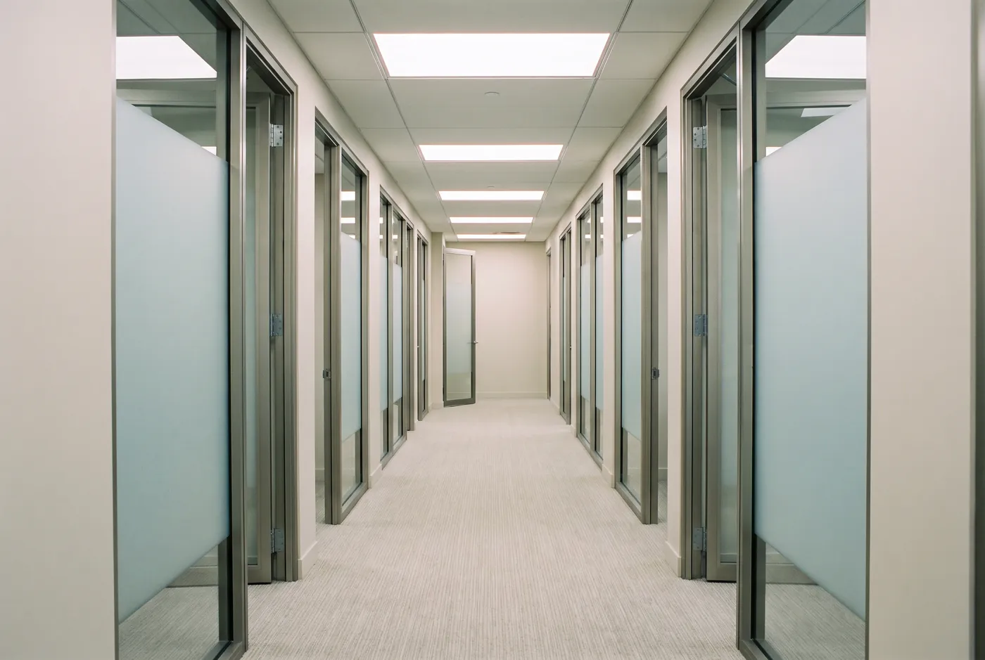 Symmetrical office corridor with frosted-glass doors