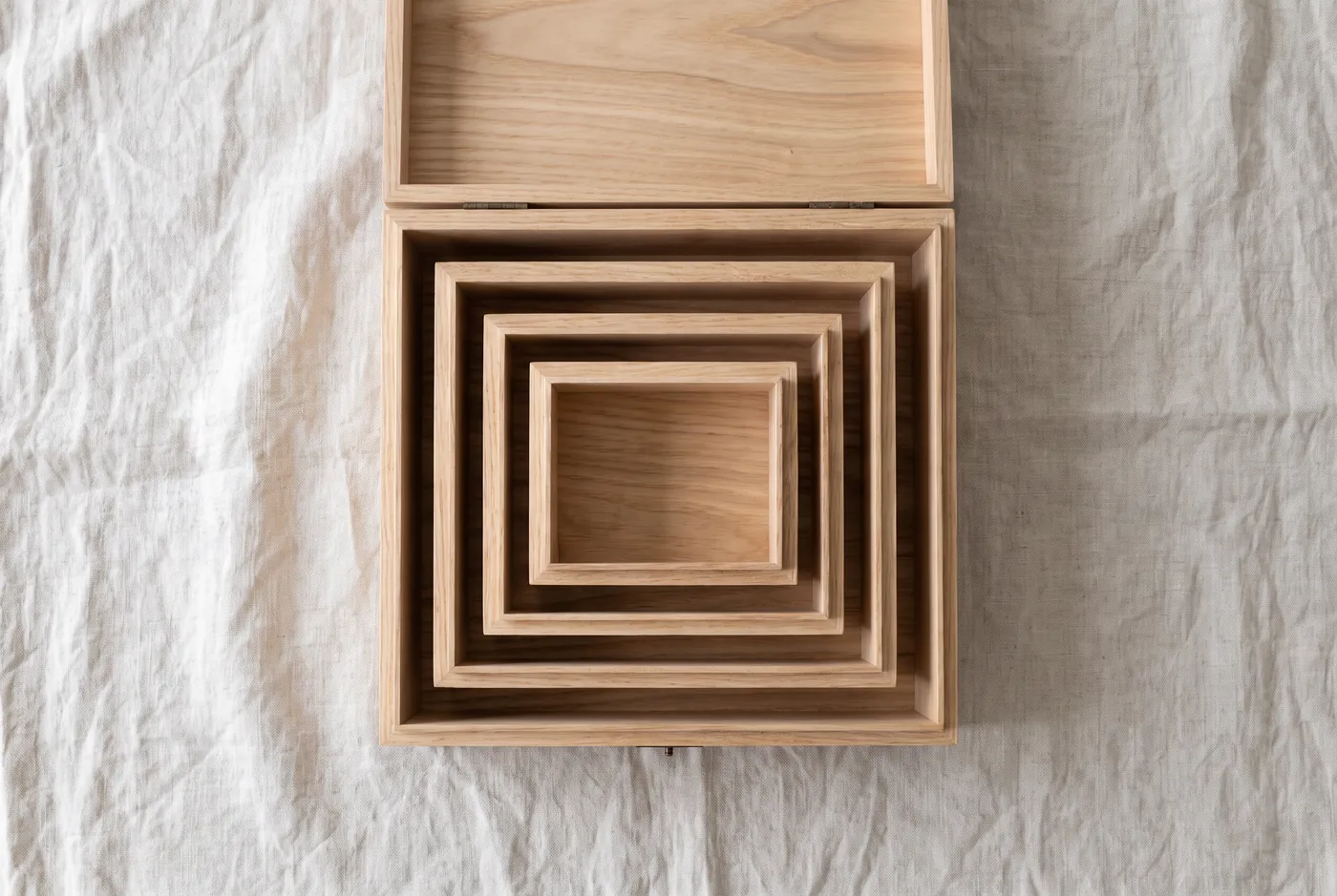 Overhead view of wooden nesting boxes of graduated sizes on linen