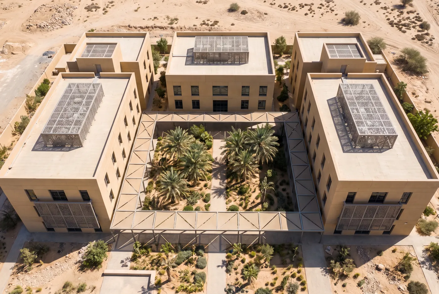 Aerial view of three office buildings joined by a walkway around a palm courtyard