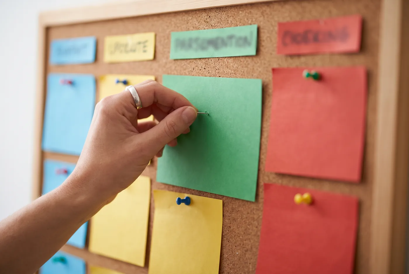 Hand placing a coloured card on a hiring pipeline board
