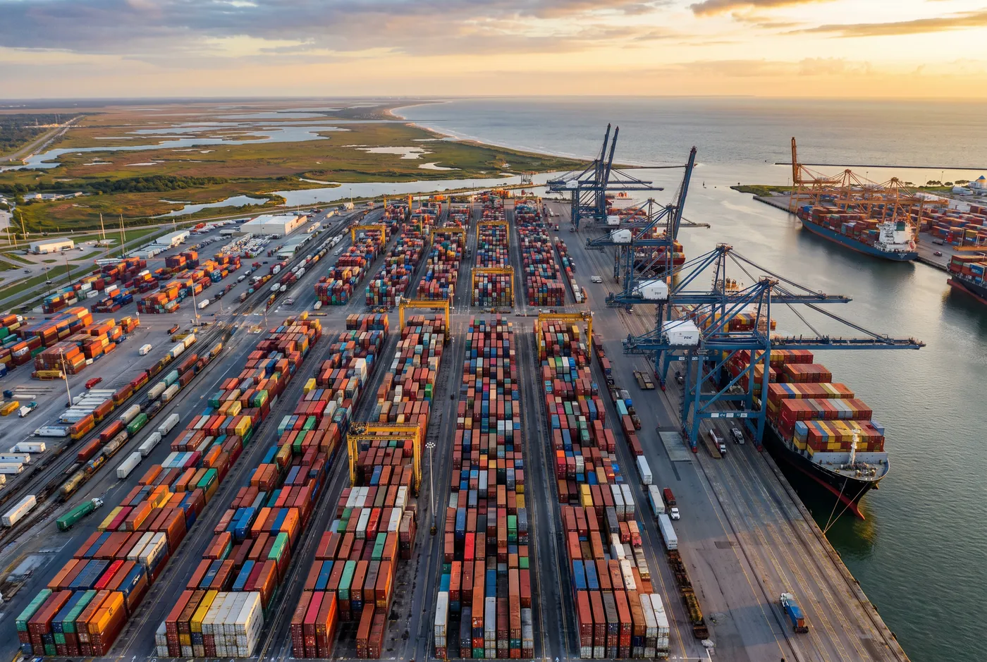 Aerial view of a container port at sunrise with gantry cranes and stacked containers